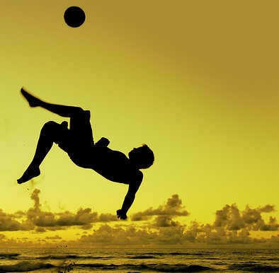 Homem chutando a bola no ar